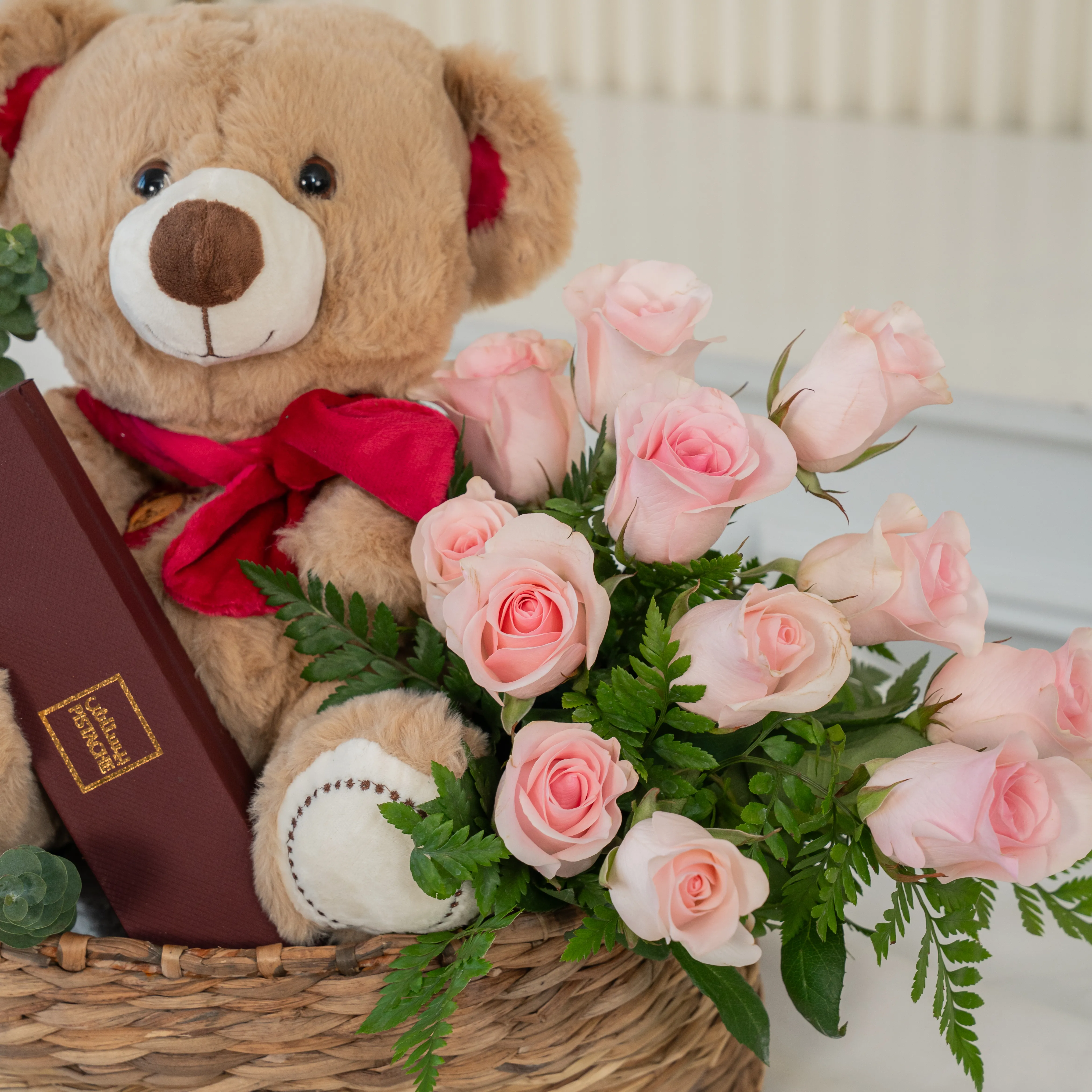 Basket arrangement of 11 red roses, 11 pink roses, small brown teddy bear and 6 Pcs Pistache Petite Indulgence Chocolate Box with green fillers.
