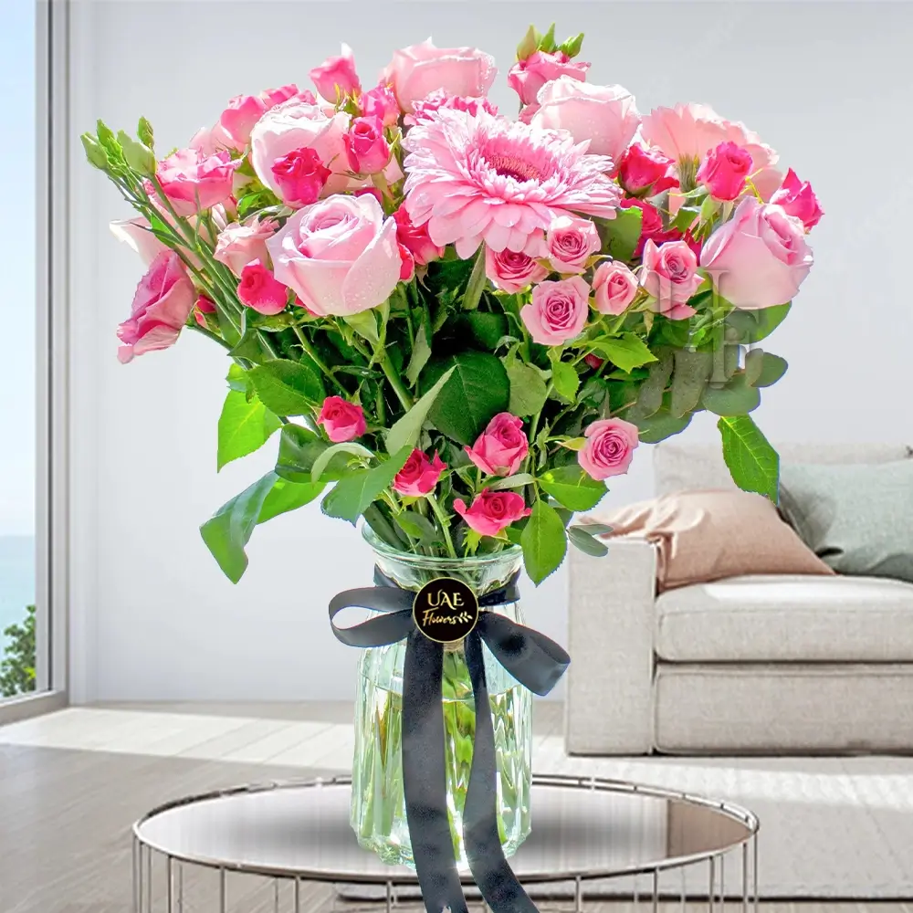 6 pink spray roses, 6 pink roses & 3 pink gerberas & fillers in a glass vase tied with black ribbon