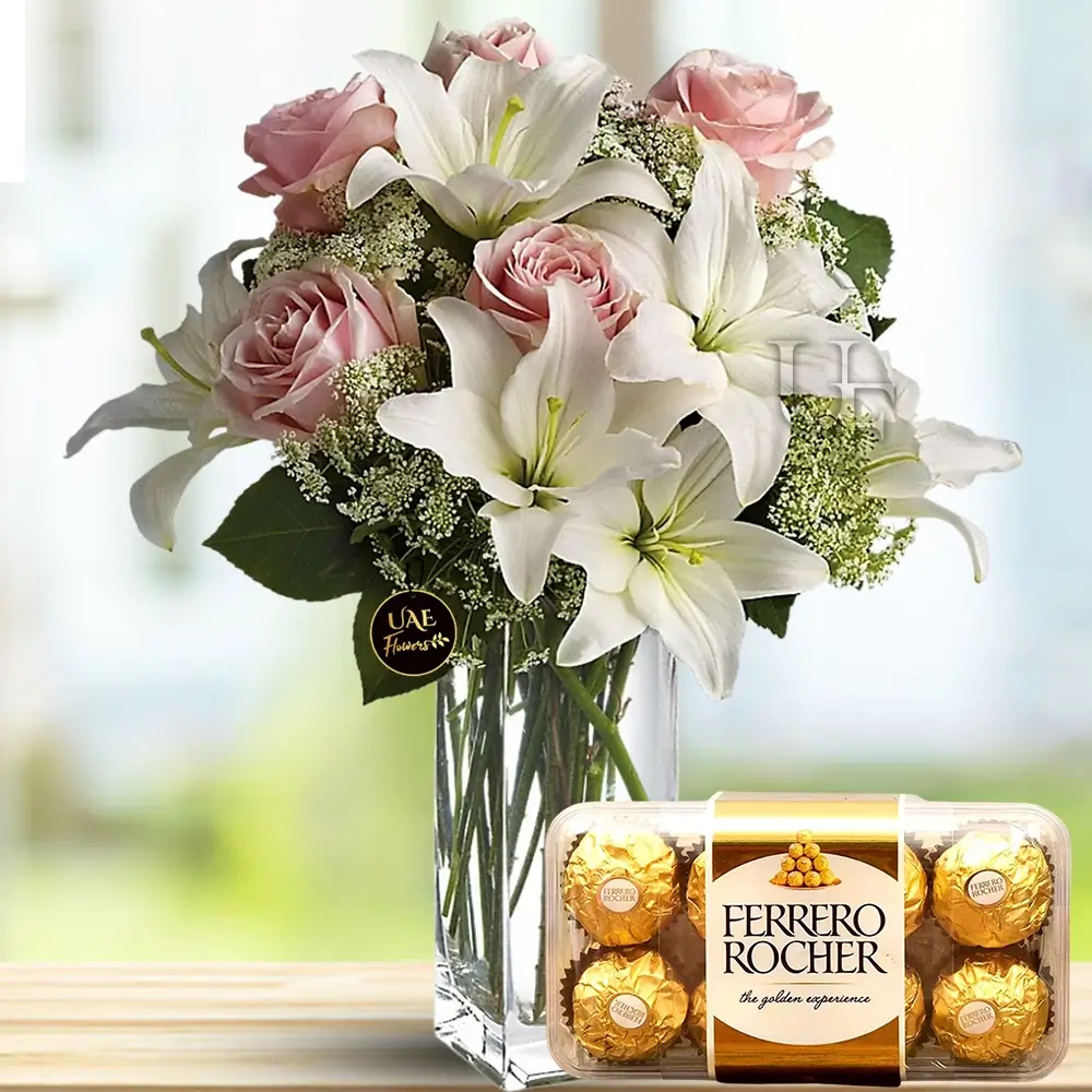 22 white lilies and 6 peach roses with fillers in a glass vase with 16 pieces ferrero rocher chocolate in a box