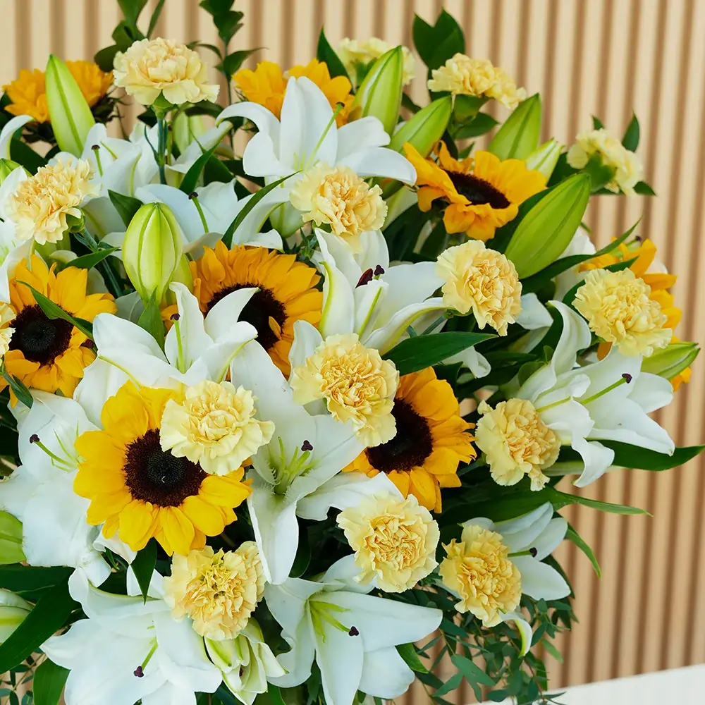 15 white lilies, 10 sunflowers & 20 peach carnations in a glass vase