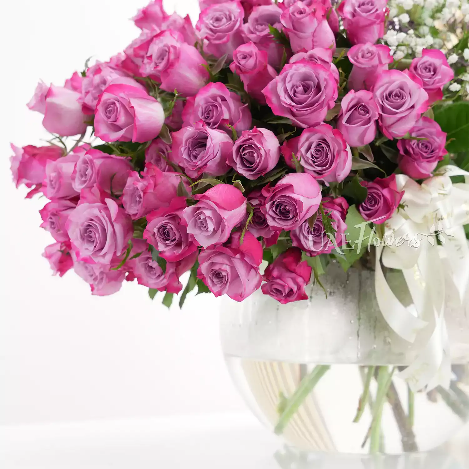 50 purple roses and 2 white lilies in a vase
