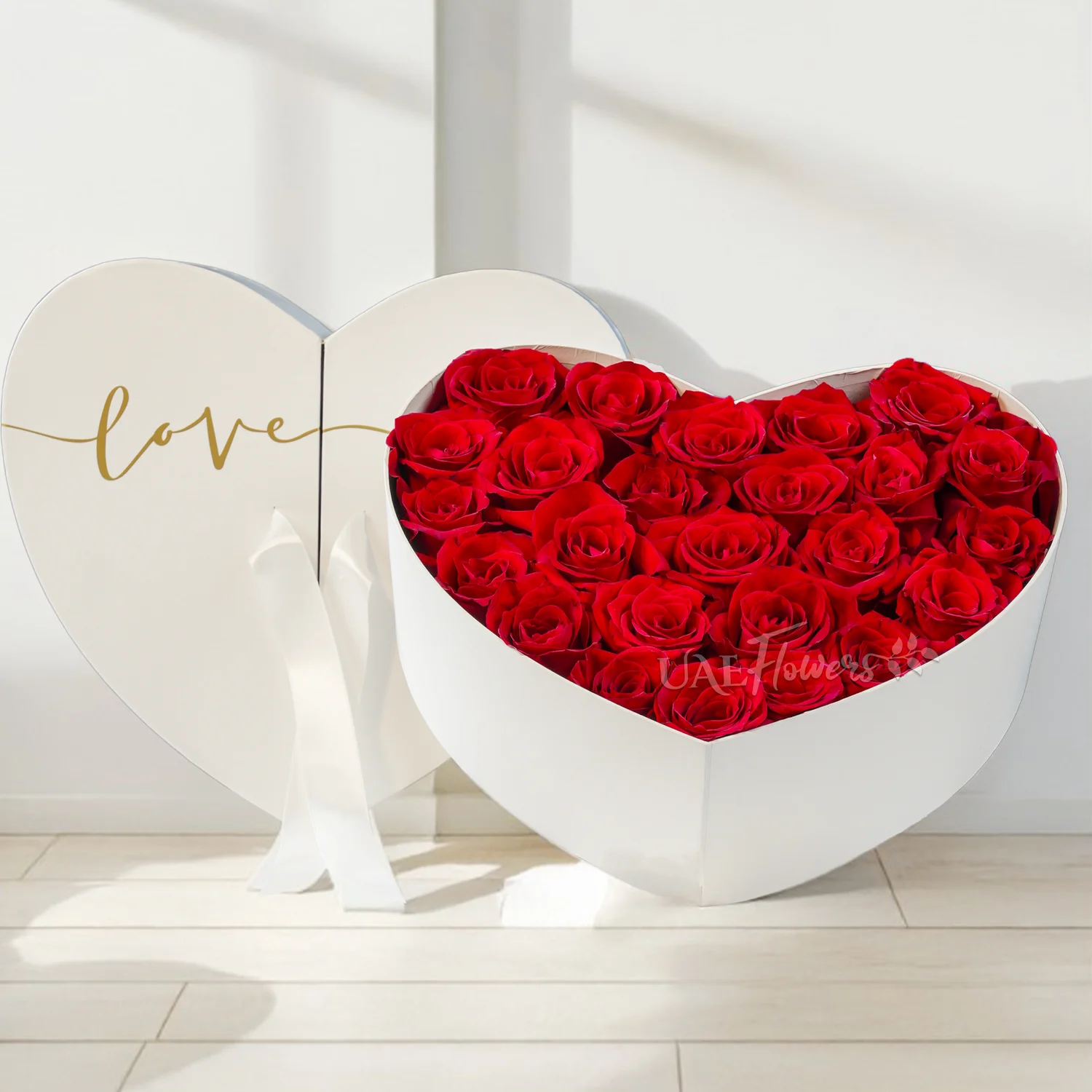 white heart-shaped box with 25 fresh red roses